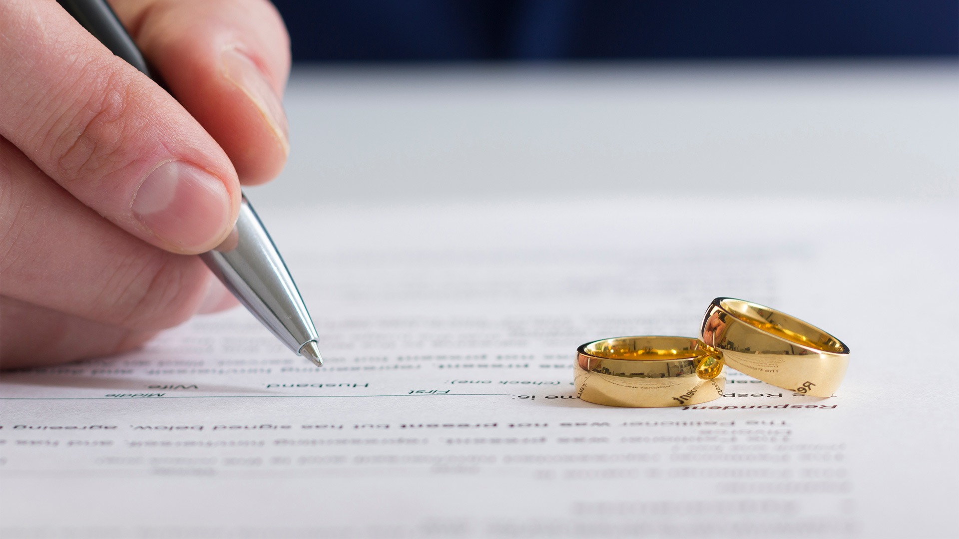 divorce lawyer hand close up writing divorce document with rings on top avondale az