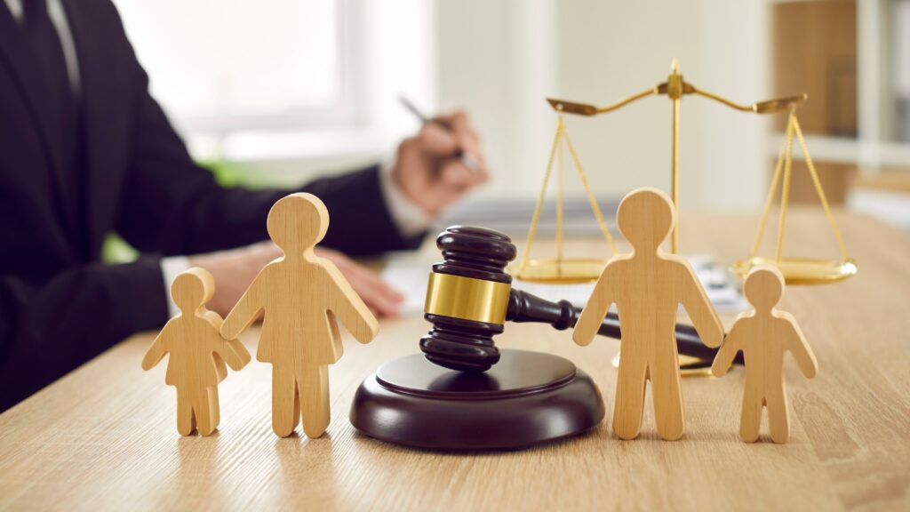 wooden family figurines and gavel on lawyers desk 1024x576